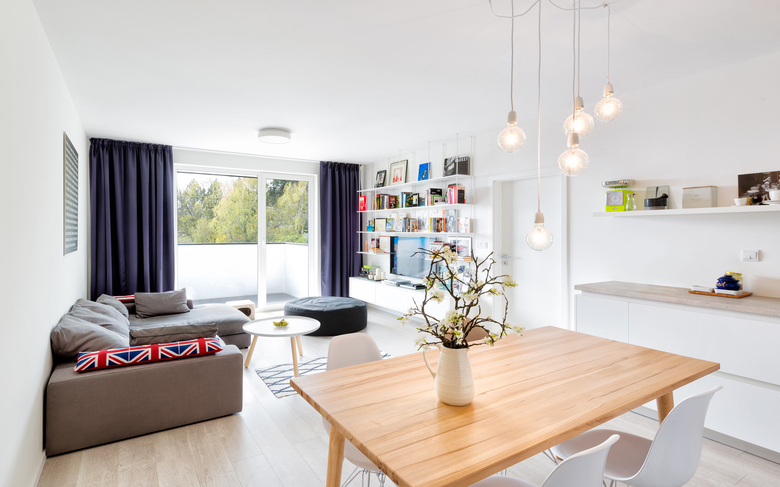 Obývačka s kuchyňou, škandinávsky dizajn, sedacia súprava, drevený jedalenský stôl, dizajnové stoličky
