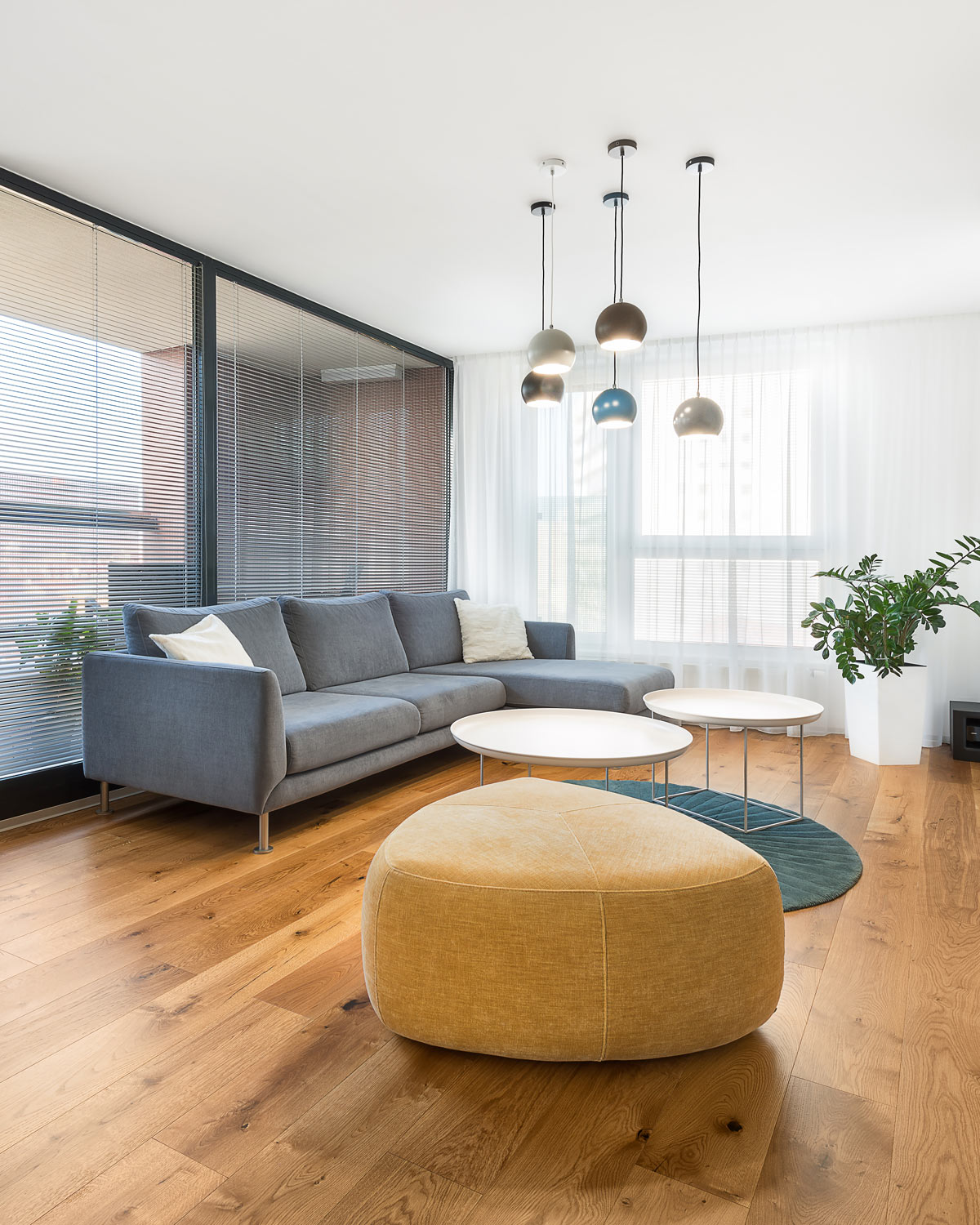 Obývačka, šedá sedačka, dánsky dizajn, osvetlenie bytu, visiace svietidlo, taburetka, dizajnový konferenčný stolík, terasa